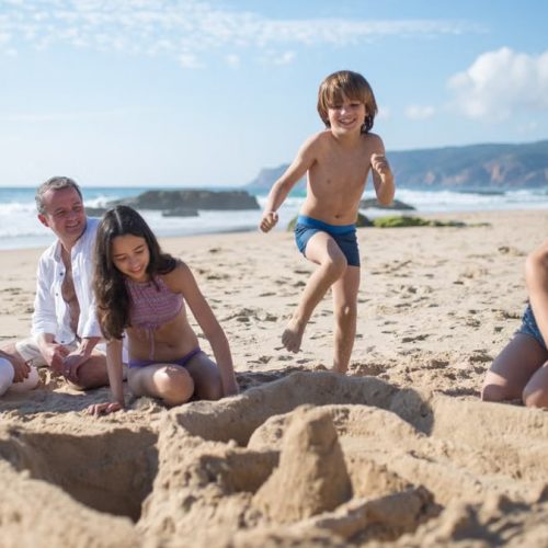 A family enjoys quality time and fun on a sunny beach, building sandcastles together.
